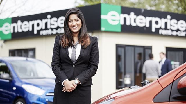 Woman in smart clothes standing in front of an enterprise rent-a-car building
